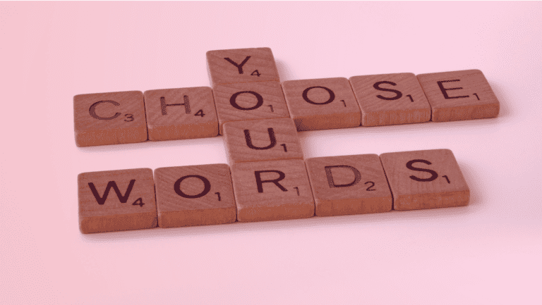 A imagem é de um grupo de blocos de madeira Scrabble com as seguintes letras: Y, A, C, H, O, S, E, U, W, R, D, dispostas para dizer CHOOSE YOUR WORDS