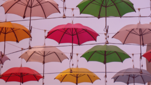 A foto é de um grupo de guarda-chuvas coloridos em Dublin, representando acessórios usados em tempos de chuva.